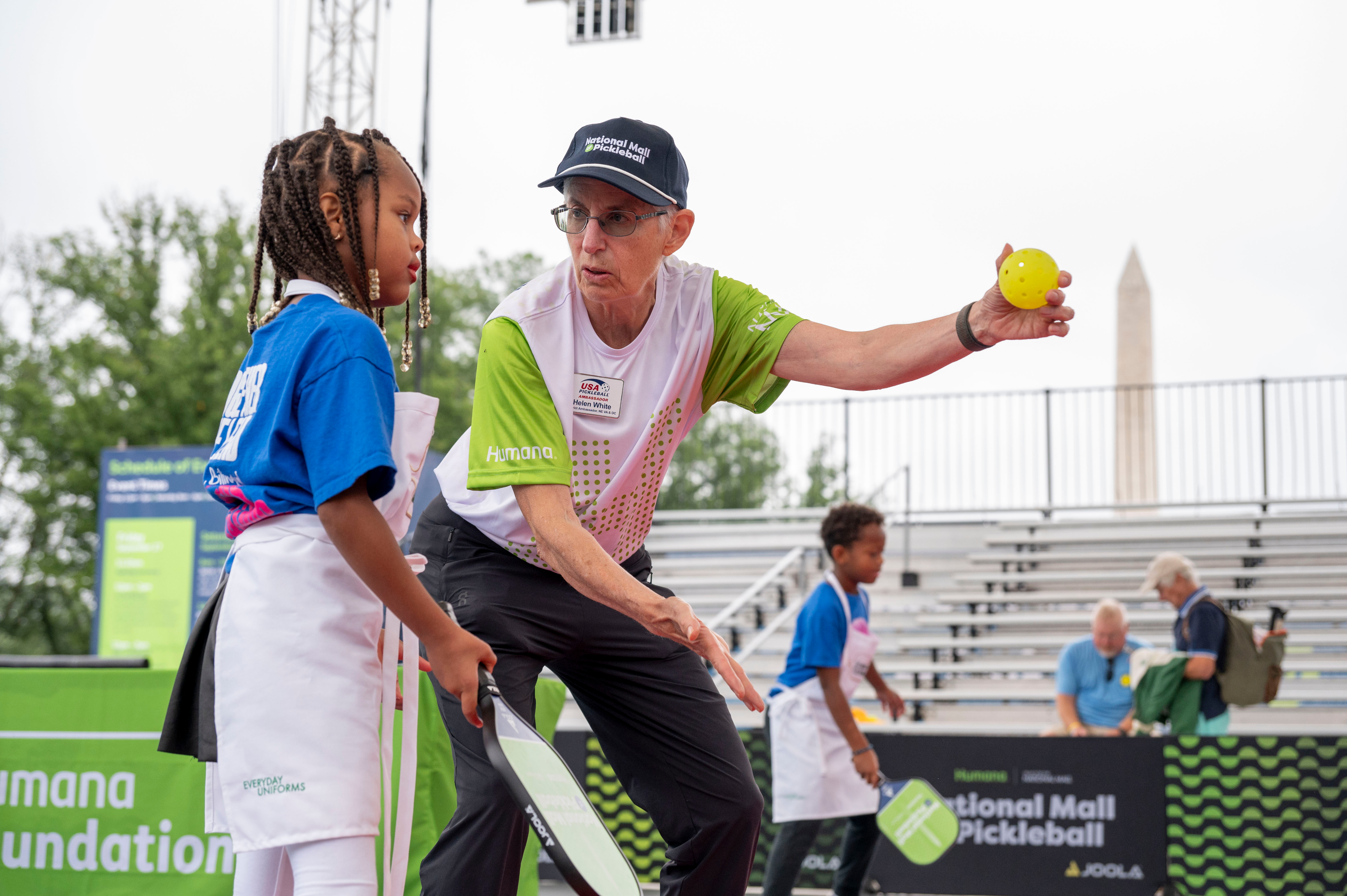 Adult coaching child on how to play pickleball.