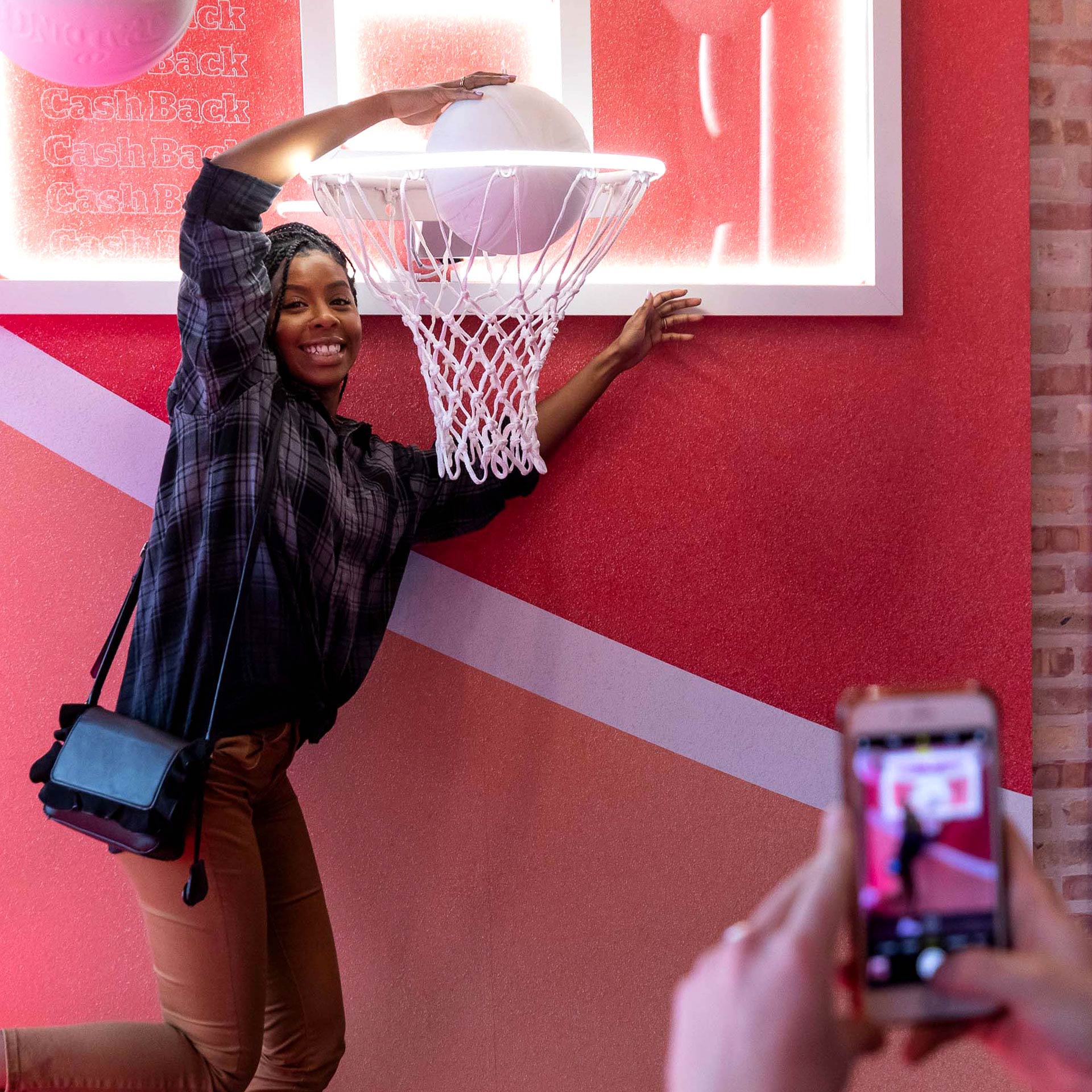 young, black woman smiles as she dunks a white-color basketball through a hoop at NBA All-Star Weekend